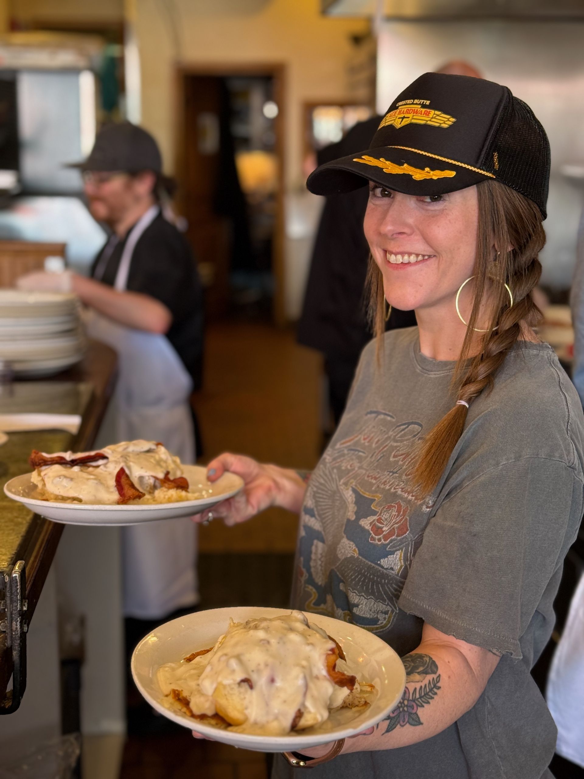 A woman is holding two plates of food in a restaurant.
