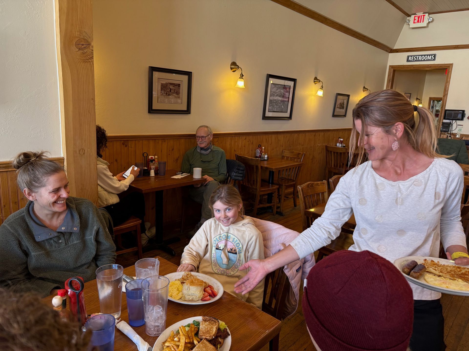 A woman is serving food to a group of people in a restaurant.
