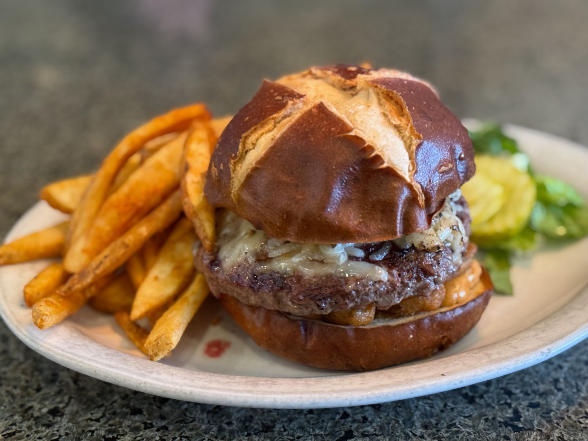 A hamburger and french fries on a white plate on a table.