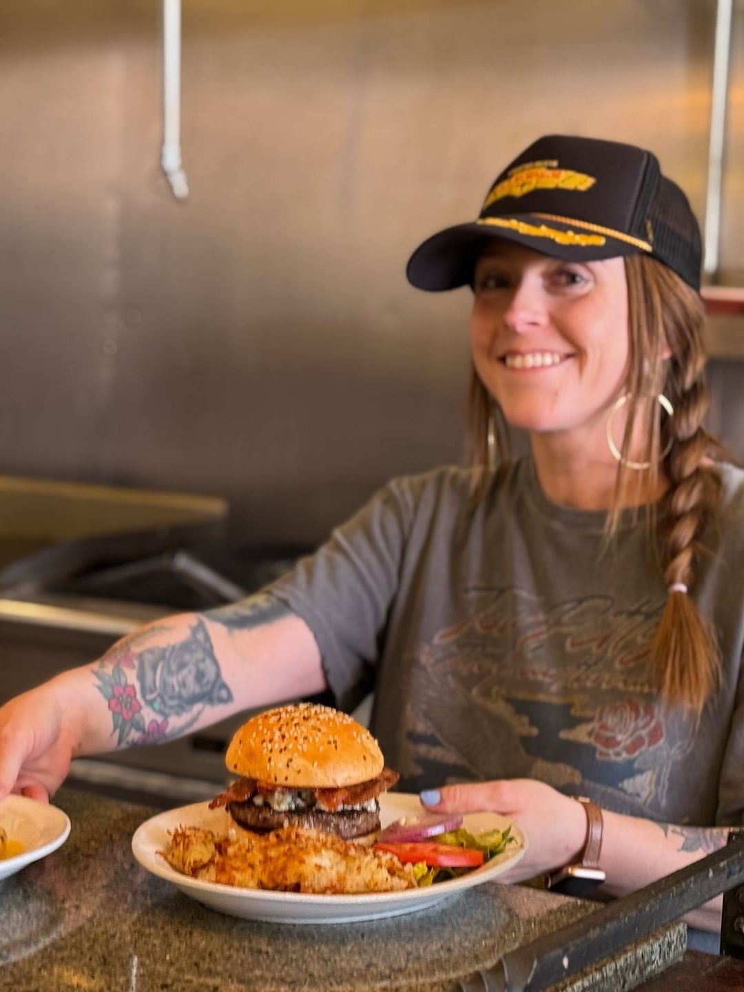A woman is holding a plate of food with a hamburger on it.