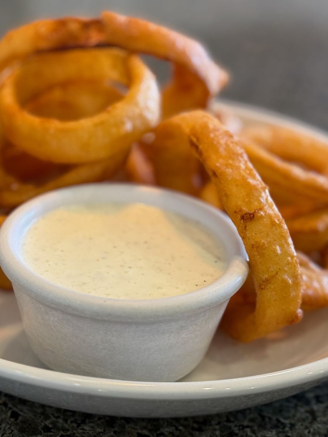 Onion rings and french fries on a plate with ranch dressing