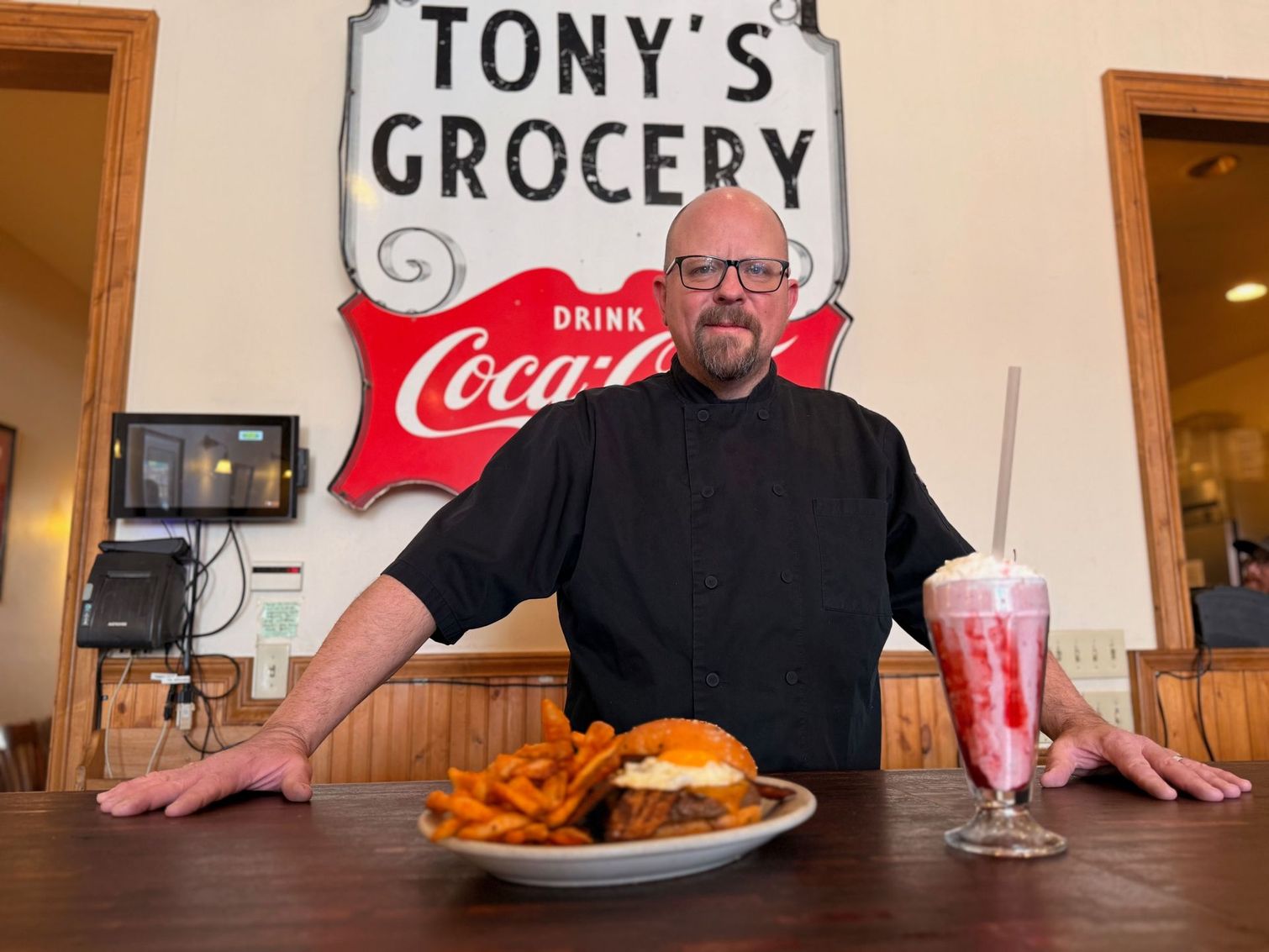 A man in a chef 's uniform is standing in a kitchen.