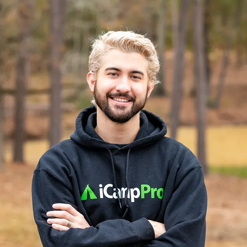 Smiling man with blonde hair and a beard wearing a black hoodie with the iCarpPro logo outdoors.