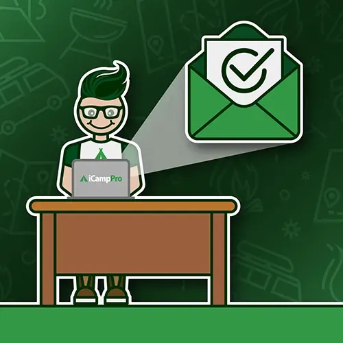 A man is sitting at a desk with a laptop and an envelope with a check mark on it.