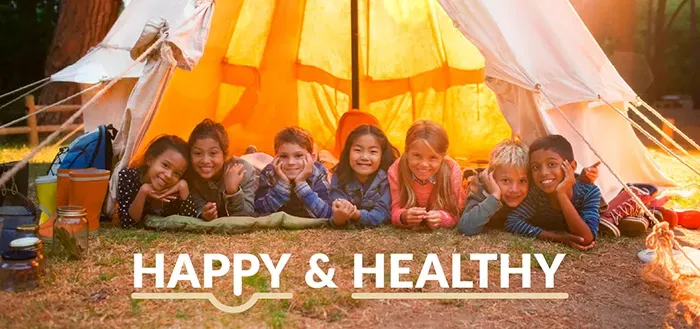 Image of happy, smiling campers inside of a tent. Text: Happy & Healthy
