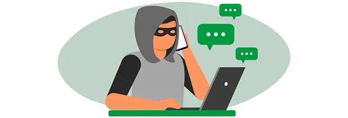 A man in a mask is talking on a cell phone while using a laptop computer.