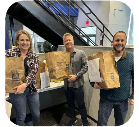 Three people holding brown paper bags