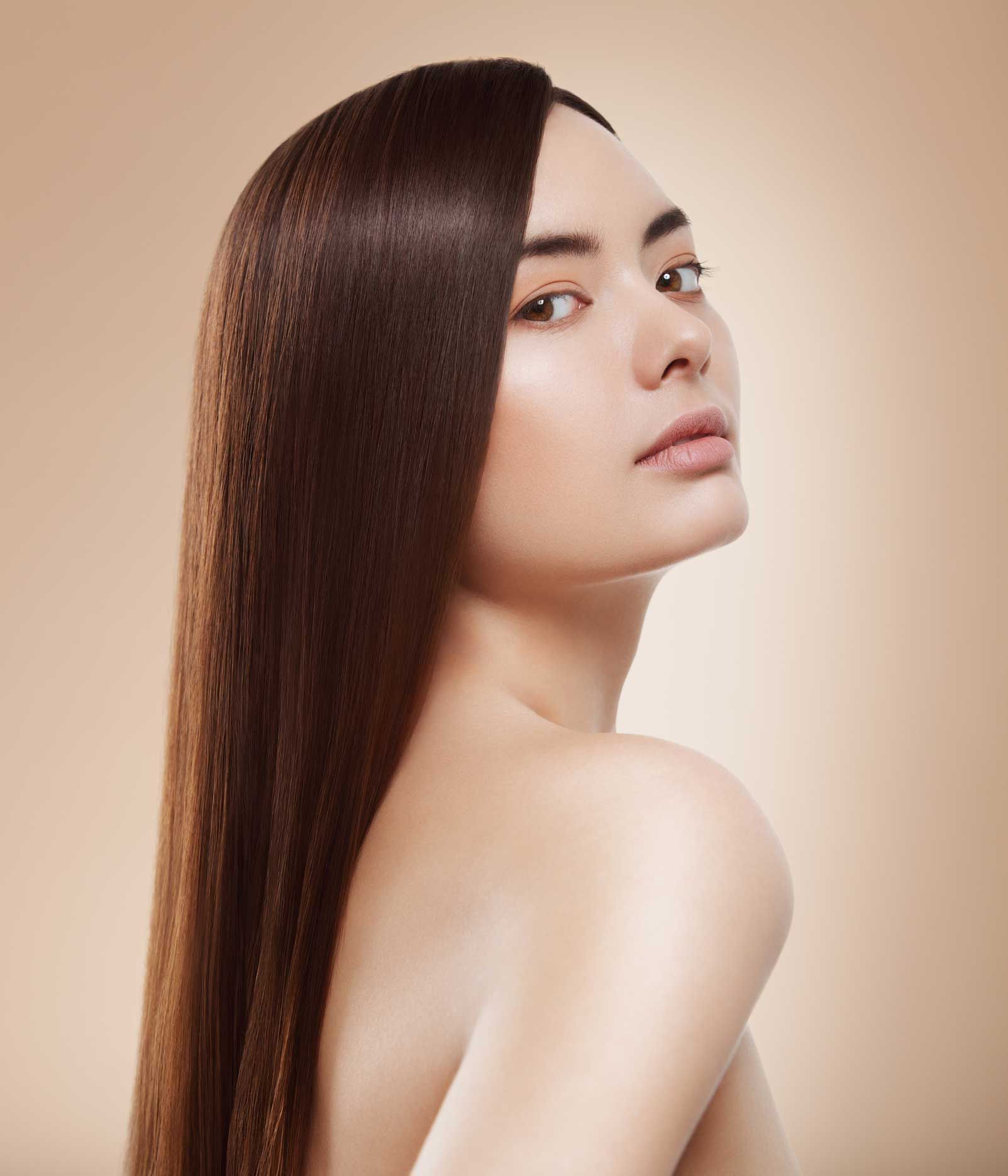 A woman with long hair is looking over her shoulder at the camera.