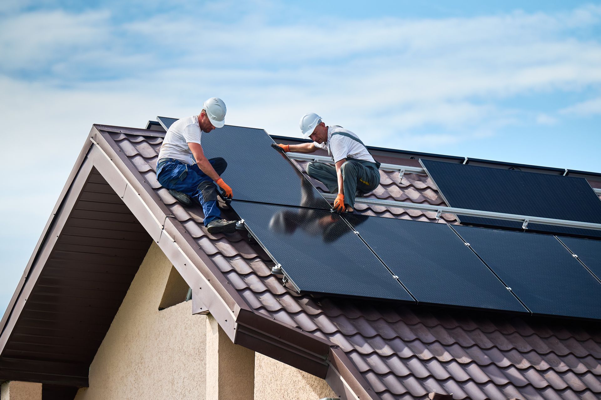 Two men are installing solar panels on the roof of a house.