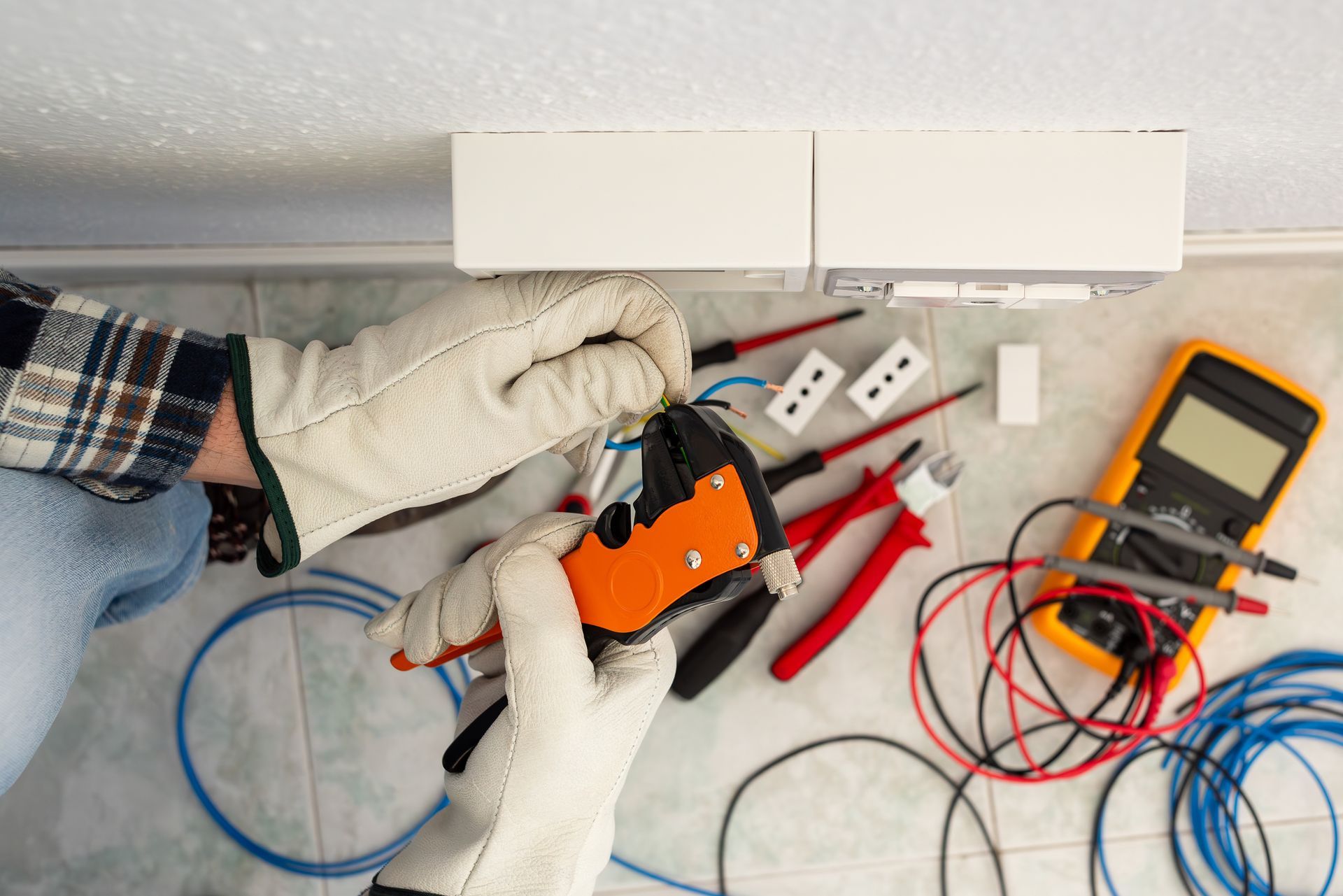Electrician with wire stripper pliers prepares the electrical cables of an electrical system.