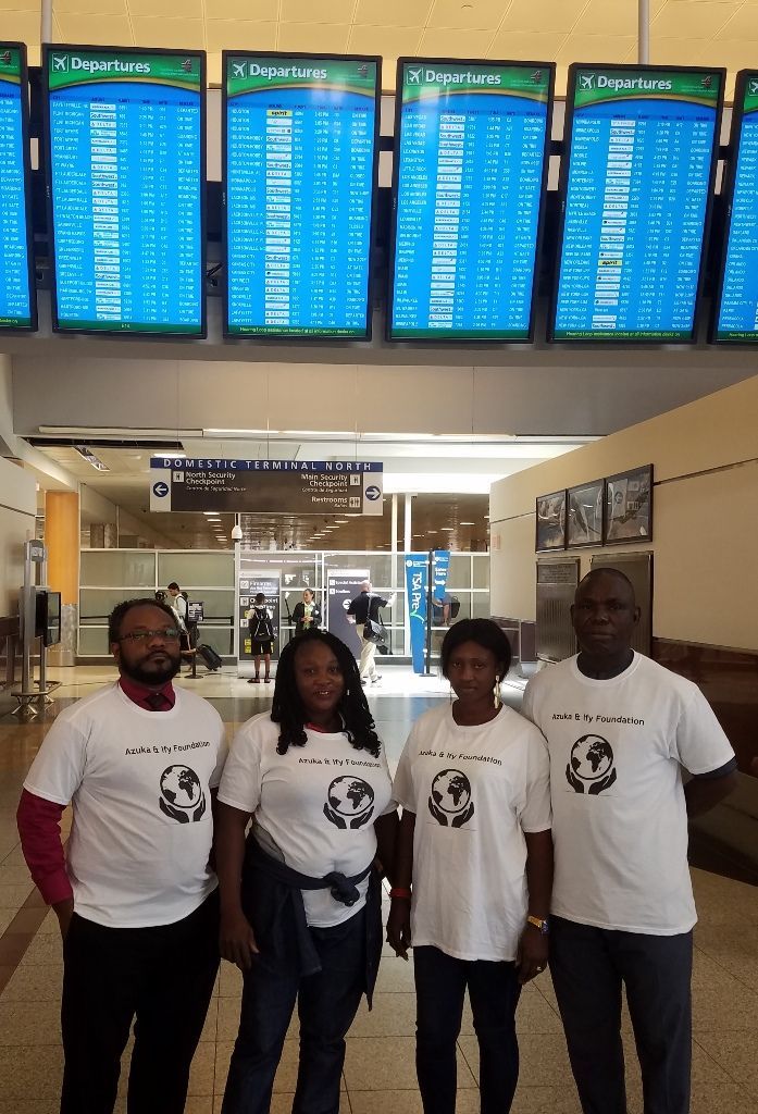 A group of people are standing in front of a large screen at an airport.