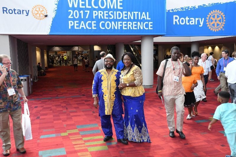 A group of people are walking in front of a sign that says welcome 2017 presidential peace conference.