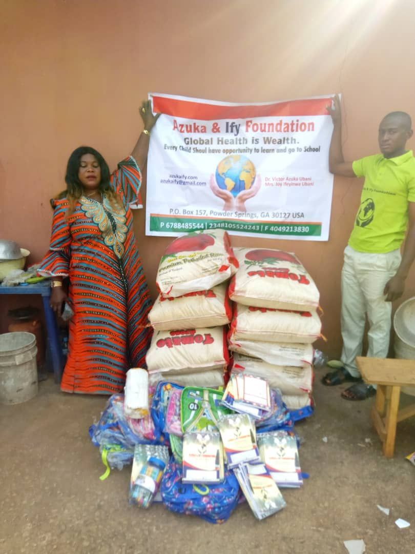 A man and a woman are standing next to a pile of bags of food.