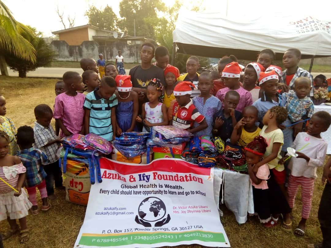 A group of children are standing around a table with a sign that says talk to us foundation.