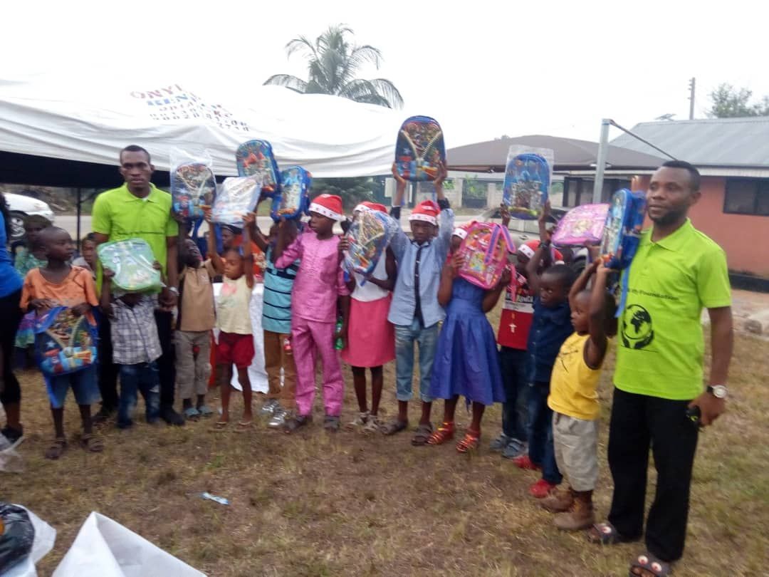 A group of children standing in front of a tent holding gifts.