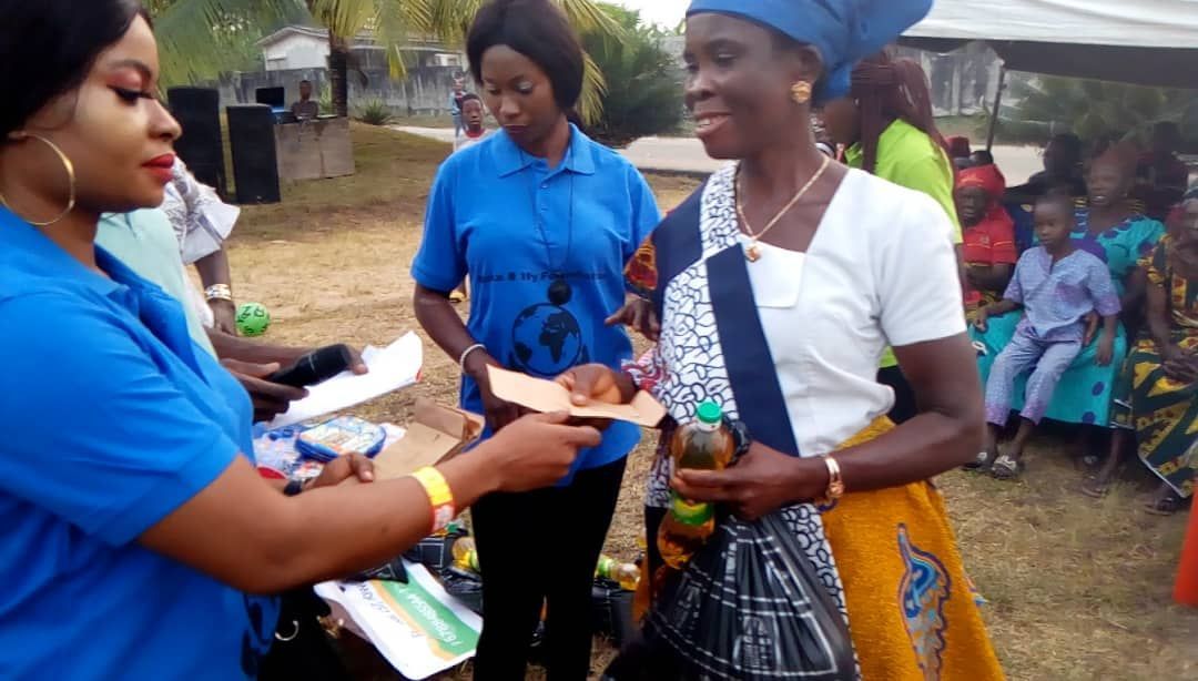 A woman in a blue shirt is handing a piece of paper to another woman.