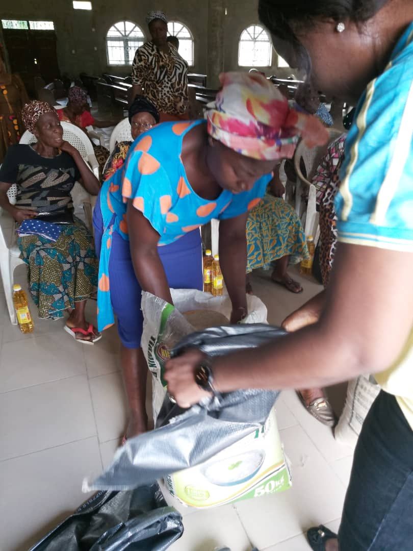 A group of people are gathered in a room and one woman is holding a bag