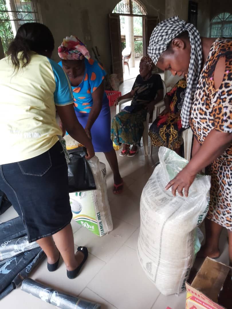 A group of women are standing around a large bag of rice