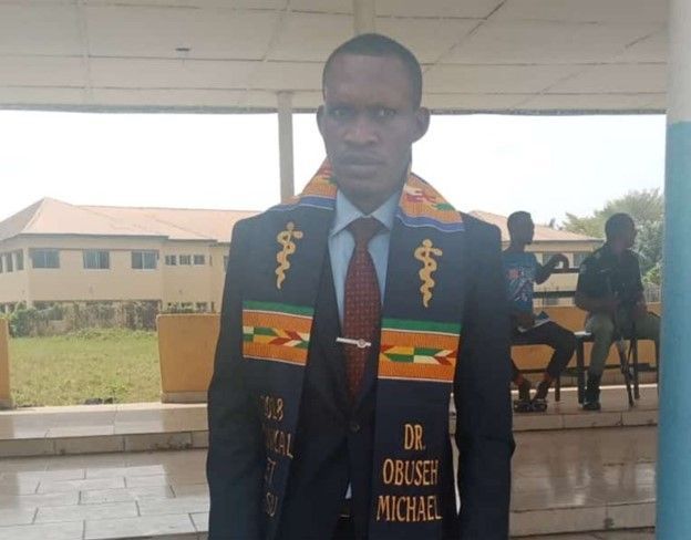 A man in a suit and tie is wearing a sash that says dr. oulsen michael