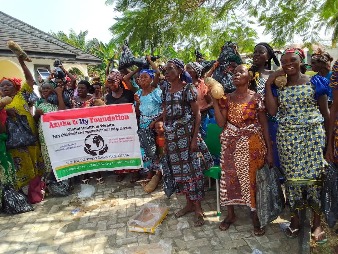 A group of women are standing in front of a building holding a sign.