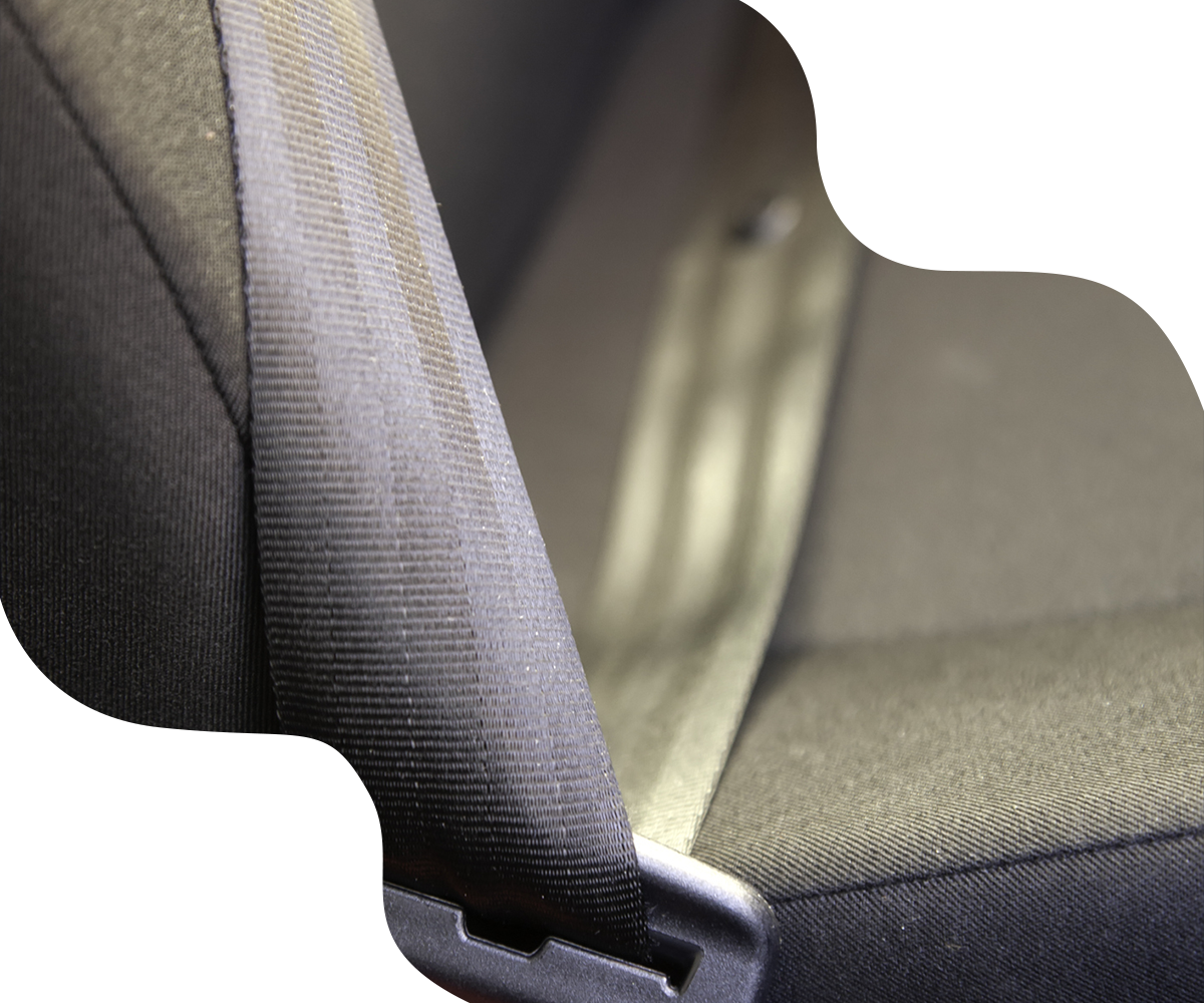 Seatbelt stretched across a car seat, black fabric against gray interior.