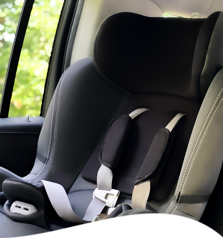 A black car seat with gray straps and a black headrest is in the backseat of a car.