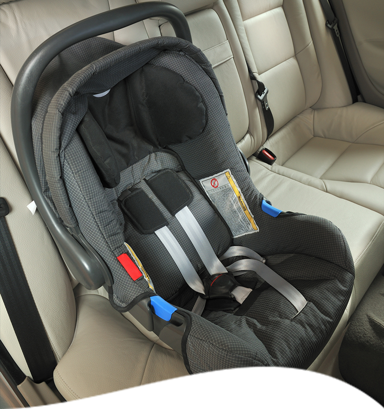 Infant car seat in gray fabric, secured in the back seat of a car with beige leather.