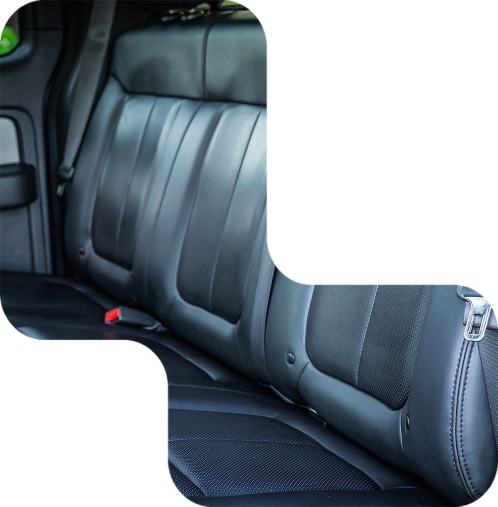Black leather car backseat with seatbelts.