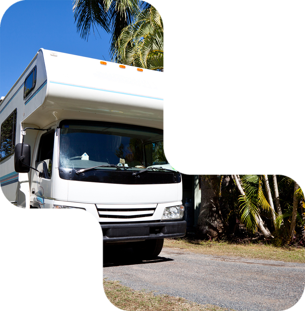 White RV parked on gravel road, palm trees in background, blue sky.