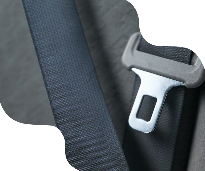Close-up of a gray seat belt buckle and webbing, clipped into place in a car.