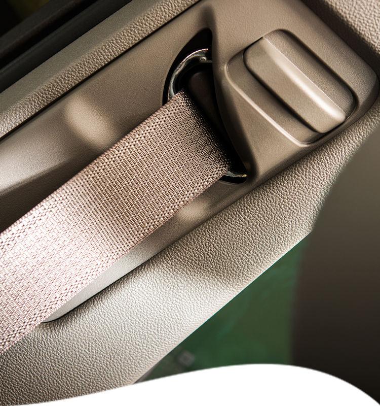 Beige seatbelt and adjustment button in a car, against a beige interior panel.