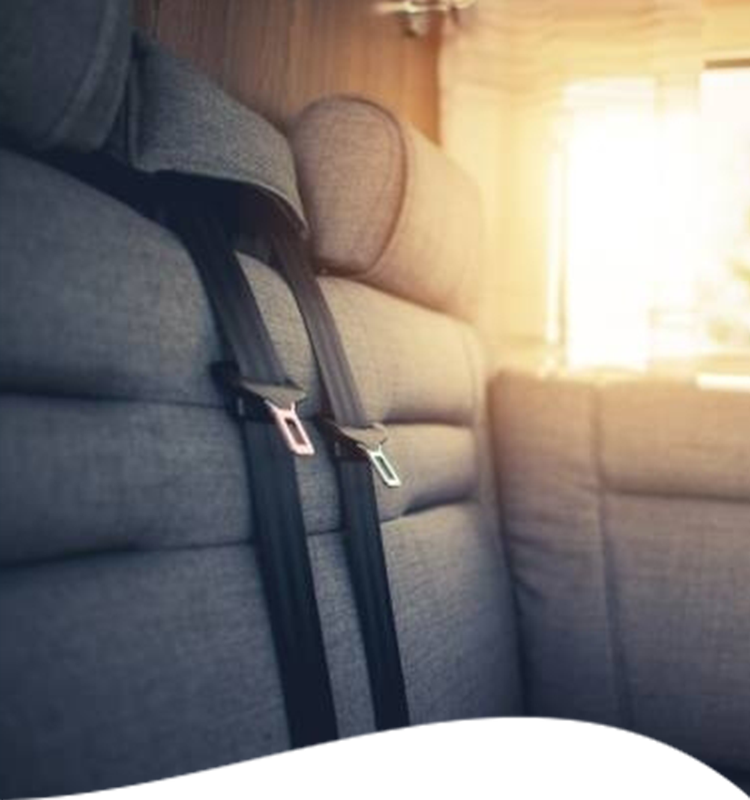 Gray RV seat with black seatbelt, sunlit window in background.