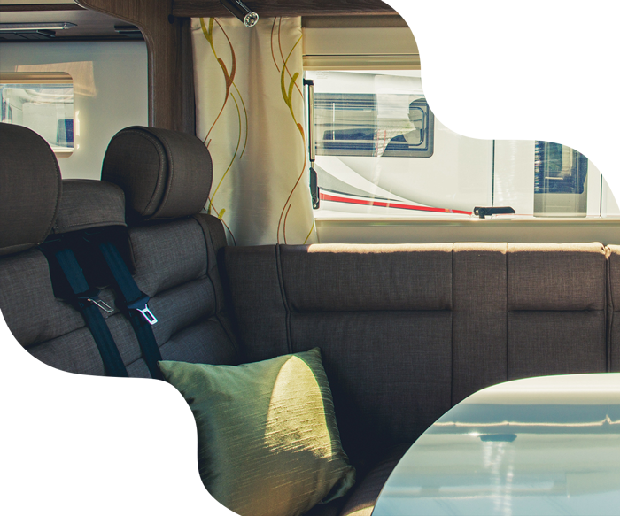Interior of a camper van featuring seating, a window, and a decorative pillow.