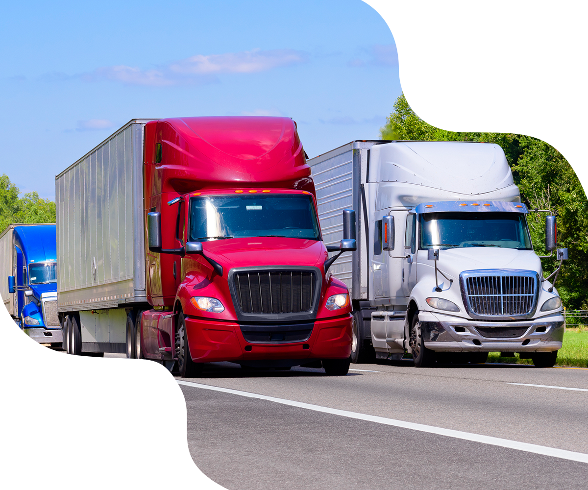 Three semi-trucks of red, white, and blue drive on a highway.