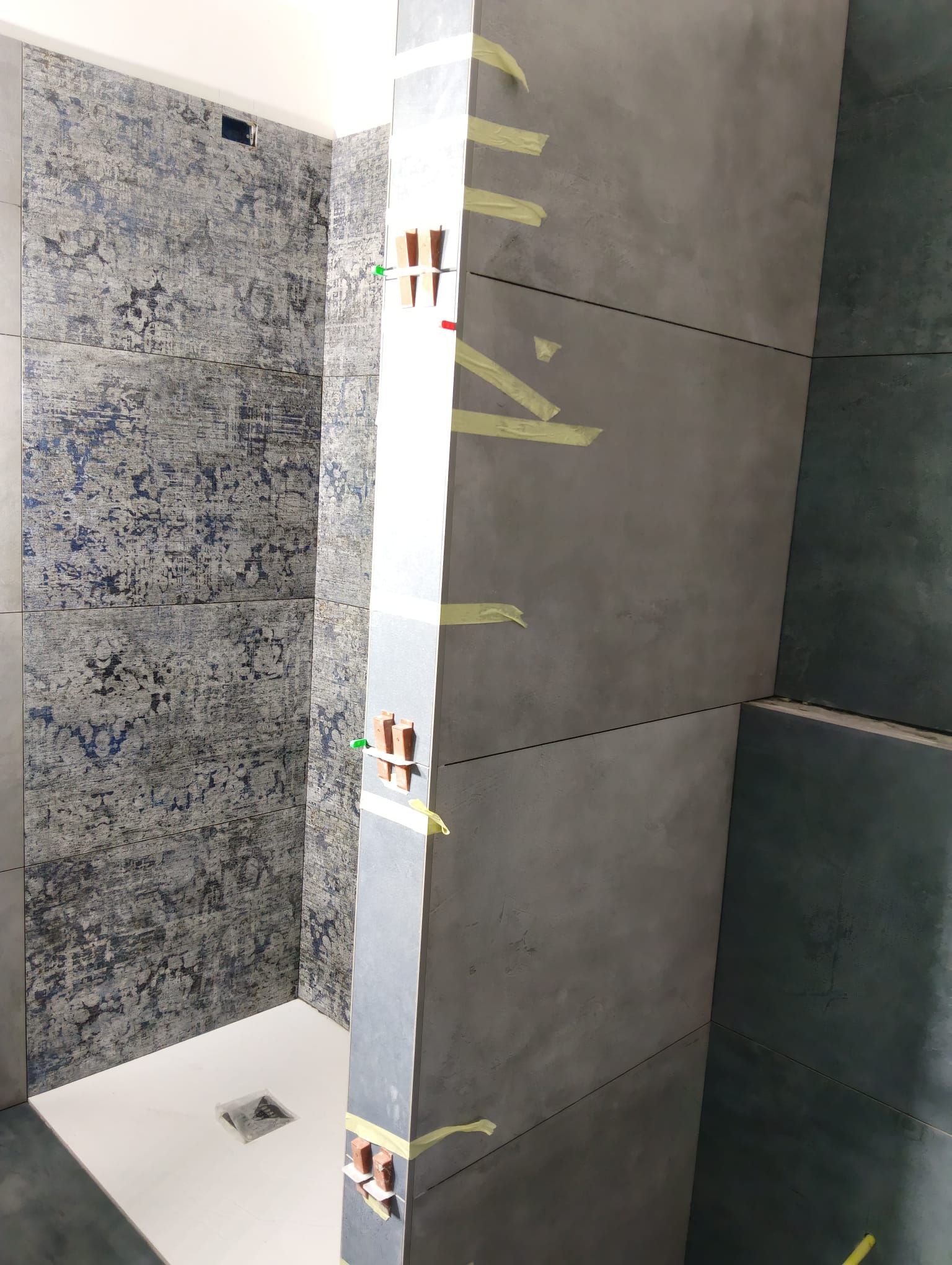 Parete della doccia o del bagno con pannelli di piastrelle grigie e fascia decorativa in piastrelle a mosaico.