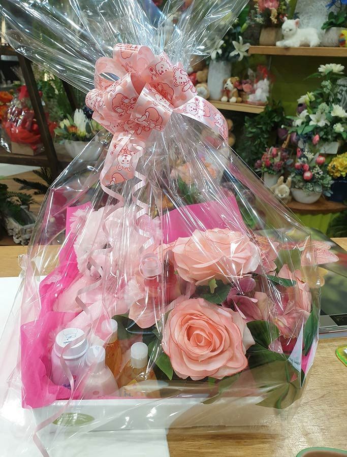 A Gift Basket Wrapped in Plastic With Pink Roses and a Pink Bow — Castletown Flower Hut in Pimlico, QLD