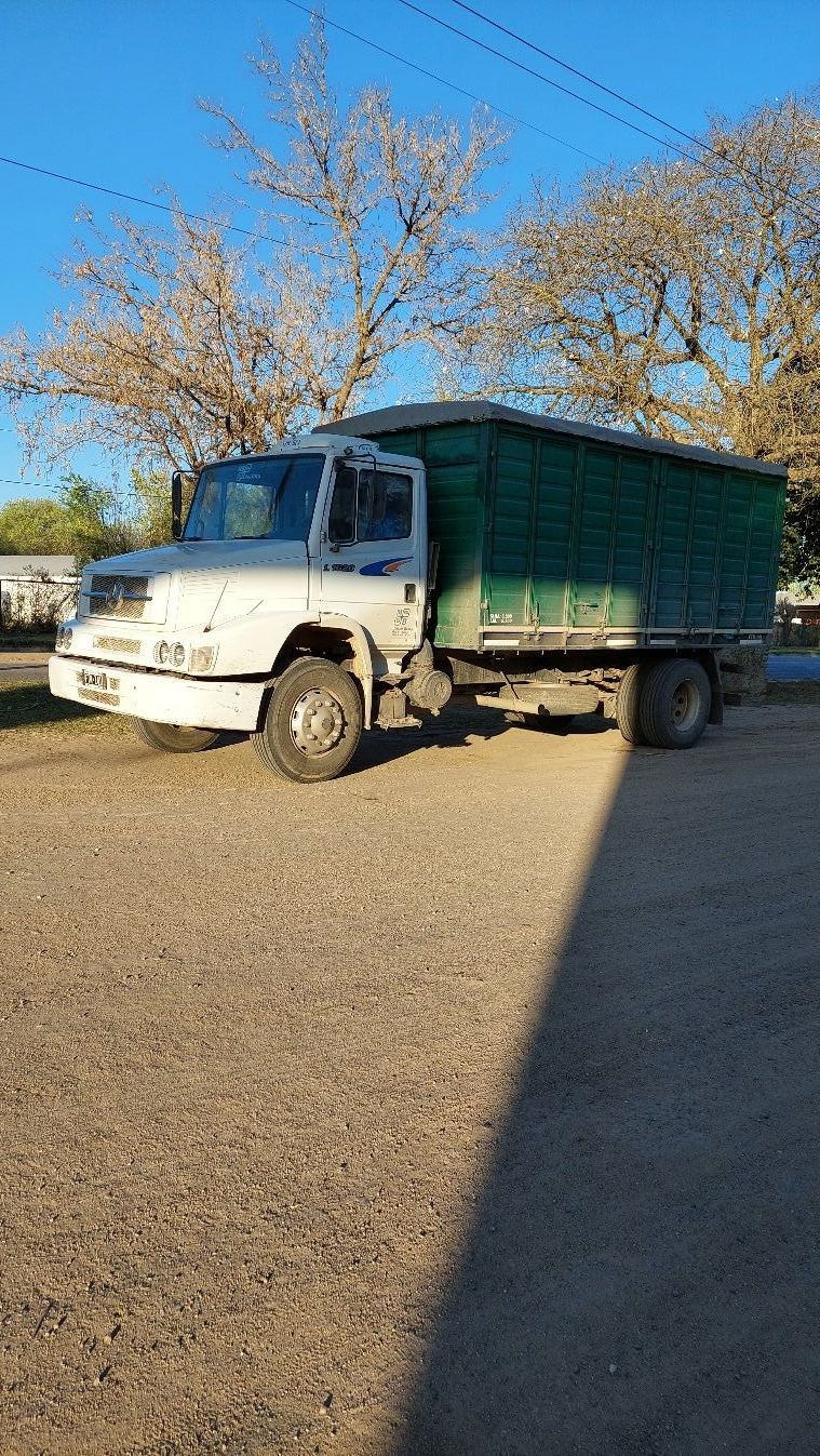 Un camión blanco y verde está estacionado en un lote de grava.