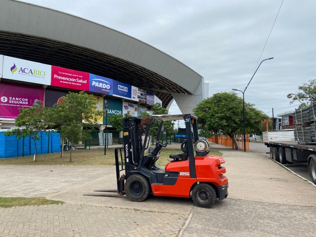 Una carretilla elevadora está estacionada frente a un gran edificio.