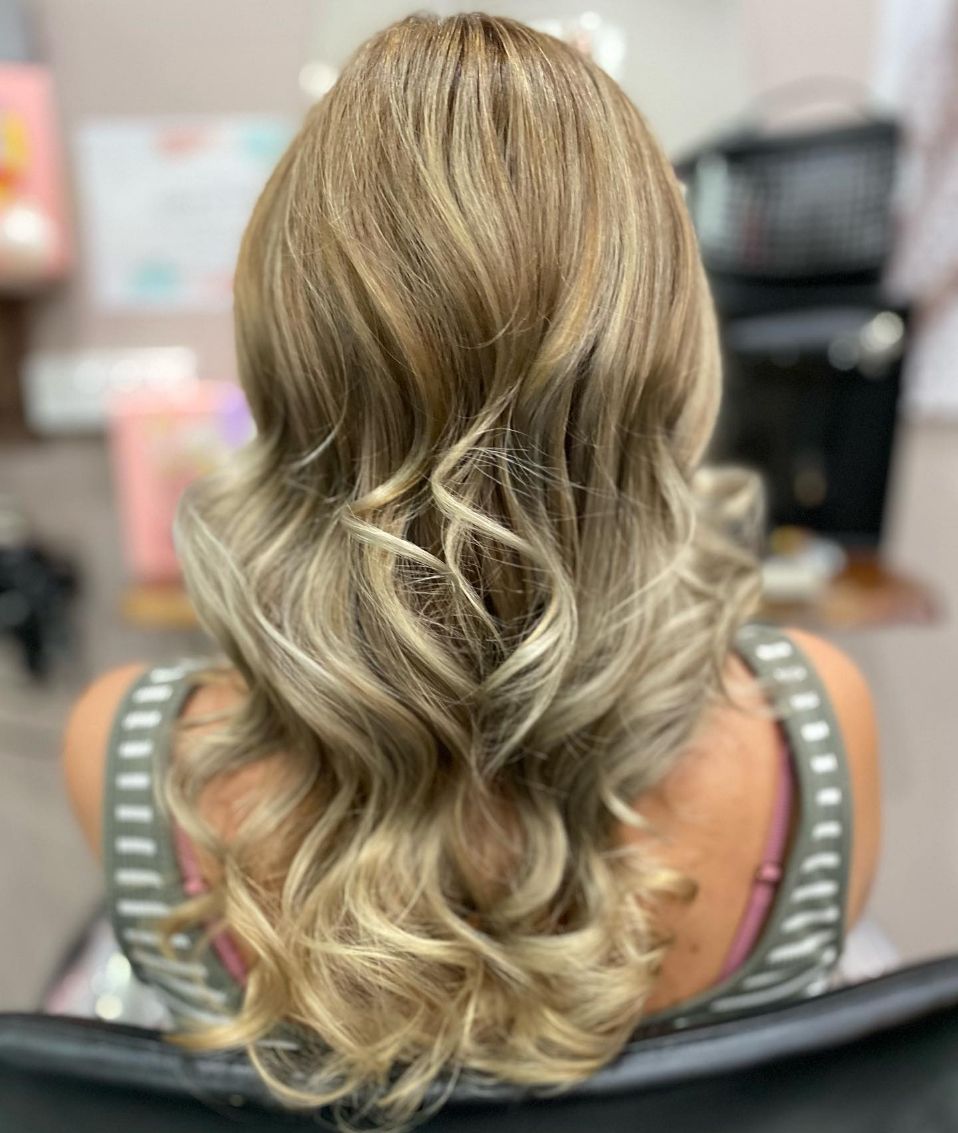 A Woman with Long Blonde Hair Is Sitting in A Chair — Ammo Hair and Beauty In Maclean, NSW