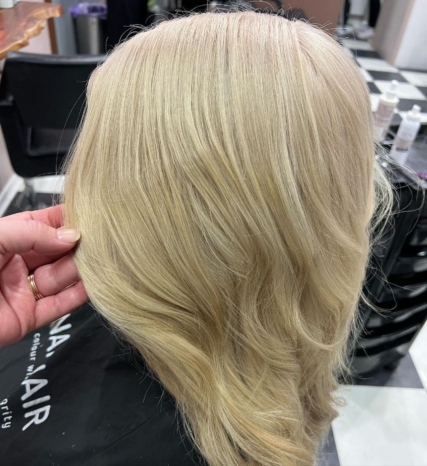 A Person Is Holding a Blonde Wig in Their Hand in A Salon — Ammo Hair and Beauty In Maclean, NSW