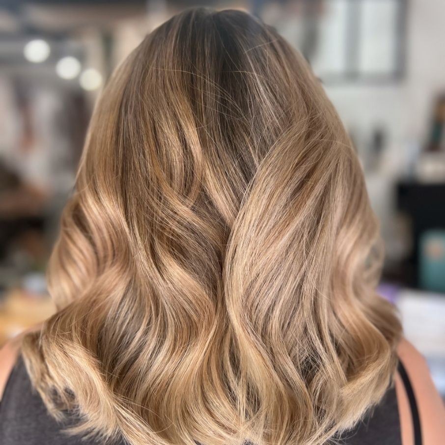 A Woman with Long Blonde Hair Is Wearing a Black Shirt — Ammo Hair and Beauty In Maclean, NSW