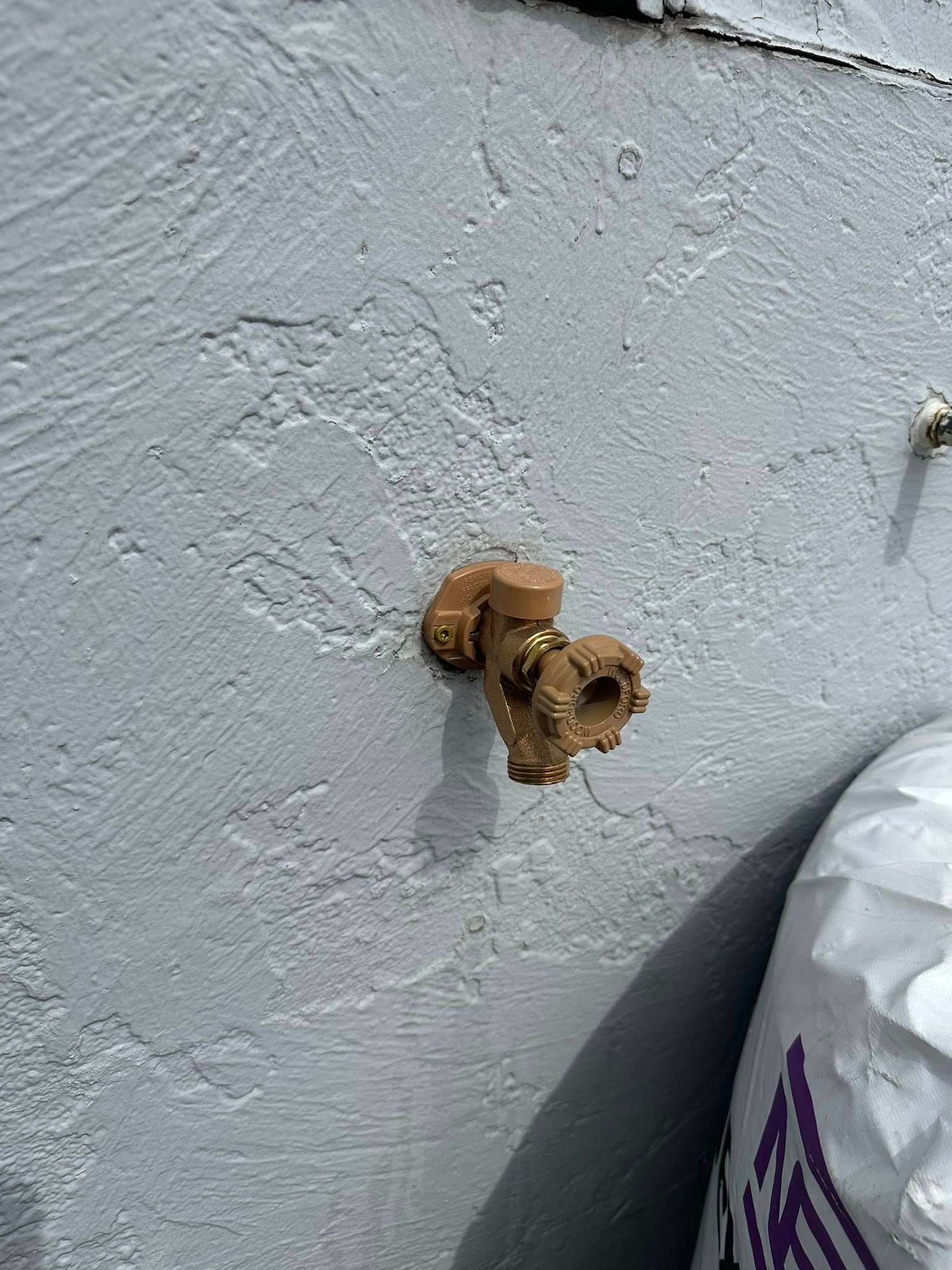 Close-up of a wall with a small rusted pipe opening and a plastic bag at the bottom right.