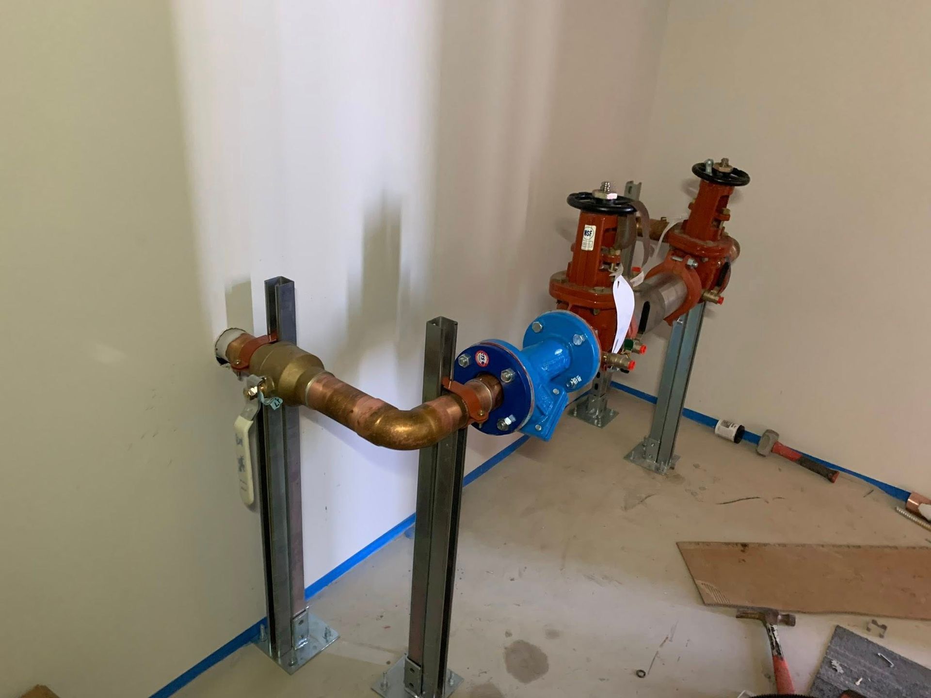 Plumbing pipes and valves installed against a wall in an unfinished room