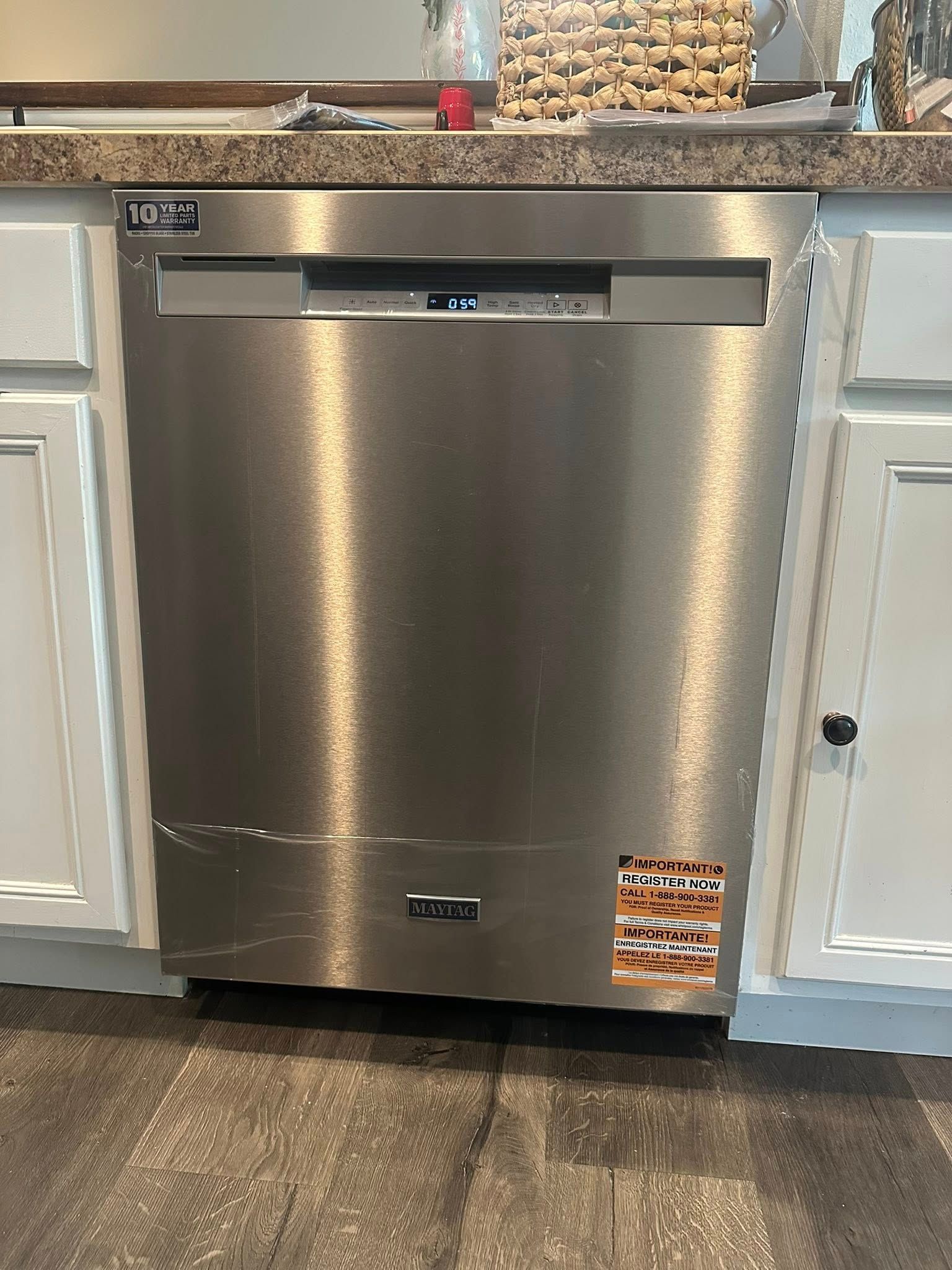 Stainless steel dishwasher under a kitchen counter, flanked by white cabinets.