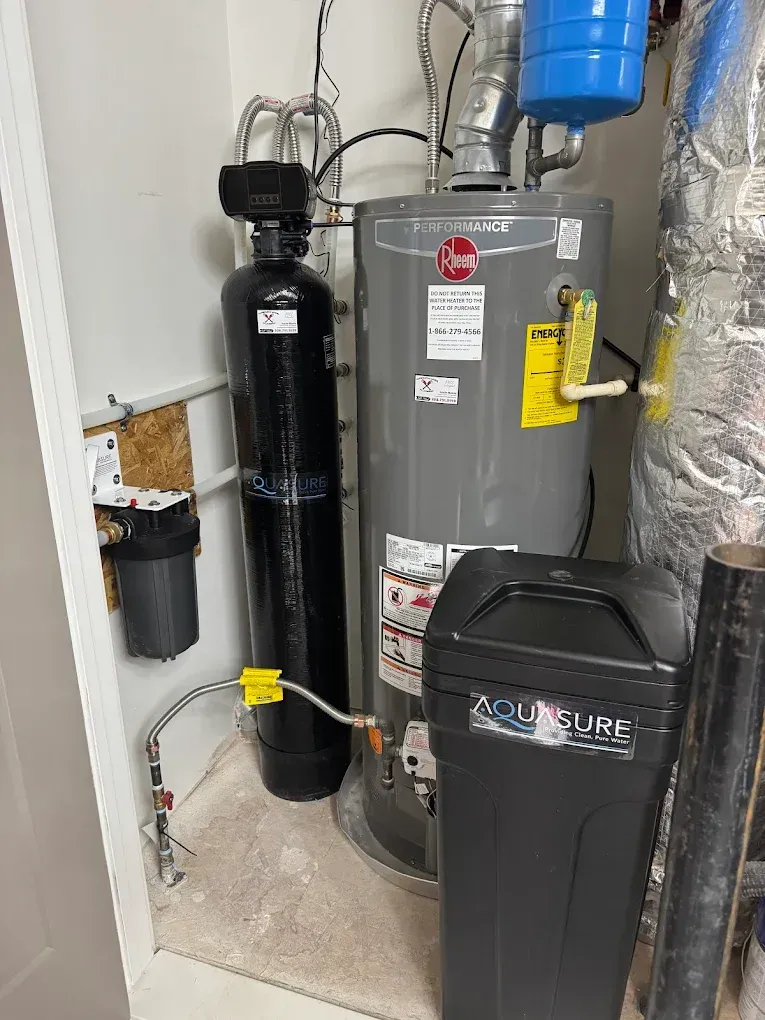 Water softener and furnace in a utility closet with pipes, valves, and ductwork.