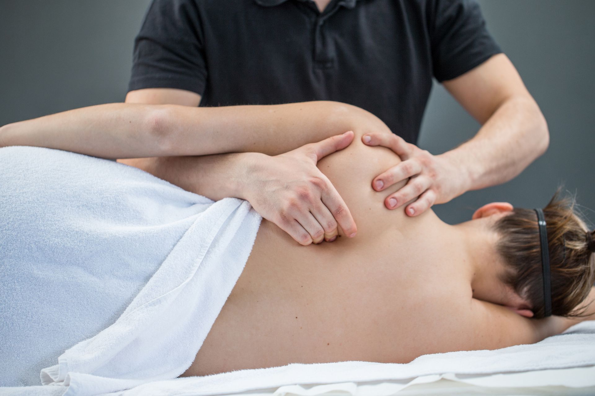 A woman is laying on a bed getting a massage from a man.