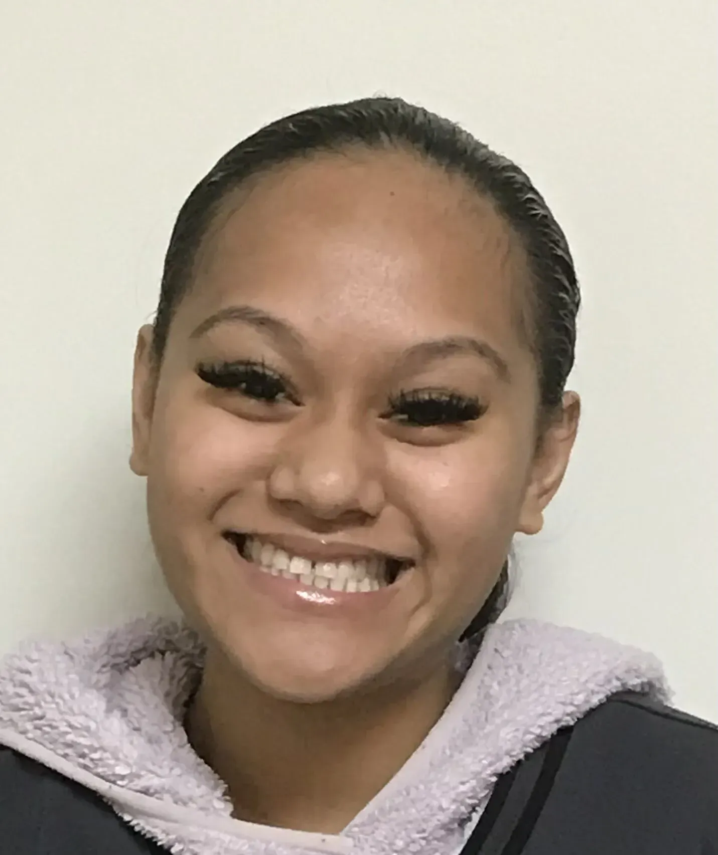 A woman wearing a purple hoodie is smiling for the camera.