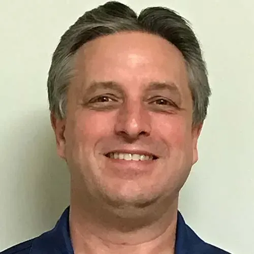 A man in a blue shirt is smiling for the camera.