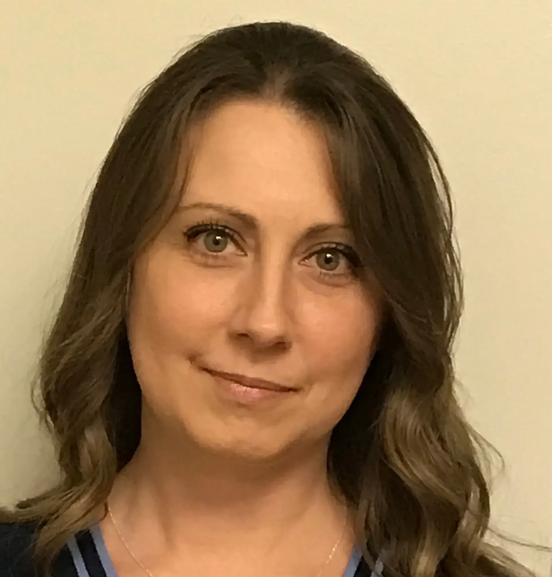 A woman with long brown hair is smiling for the camera.