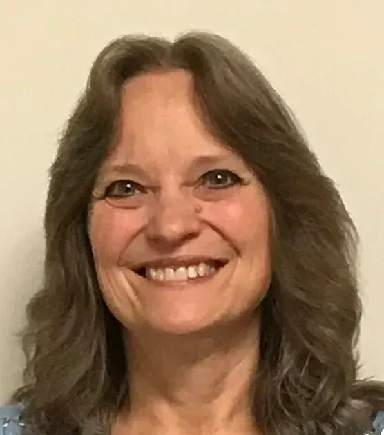 A woman with long brown hair is smiling for the camera.